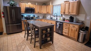A modern kitchen with wooden cabinets, a stainless steel refrigerator, a microwave, and a dining area with a table and chairs. - Charming 3-bedroom house with hot tub in Bailey, perfect for relaxing stays (Bailey)