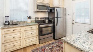 A kitchen with a microwave, toaster, kettle, and stainless steel appliances. - Gull Cottage (Tybee Island)