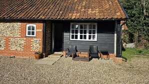 A small building with a tiled roof, a stone wall, and a gravel driveway. - Dickleburgh Crown (Diss)
