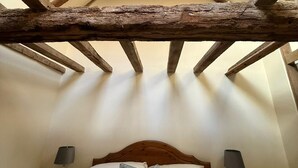 A bedroom with a wooden ceiling, a bed with white bedding, and two bedside tables with lamps. - Dickleburgh Crown (Diss)