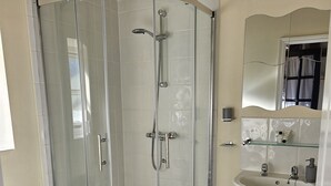 A bathroom with a glass-enclosed shower, a white sink, and a toilet. - Dickleburgh Crown (Diss)