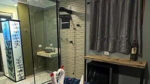 A modern hotel room with a glass-enclosed shower, a bed with a white and blue duvet, and a hanging light fixture. - Tico Pousada - Campos do Jordão (Campos do Jordão)