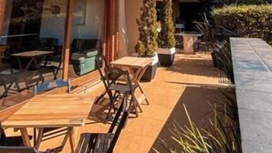An outdoor patio with tables and chairs, a thatched roof, and a view of the surrounding landscape. - Tico Pousada - Campos do Jordão (Campos do Jordão)