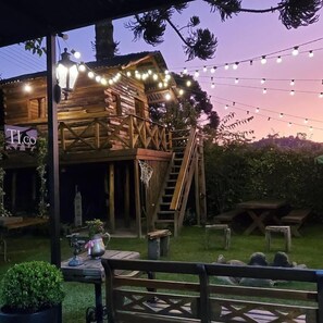 A rustic wooden cabin with a balcony, string lights, and a sign reading 'TI.CO'. - Tico Pousada - Campos do Jordão (Campos do Jordão)