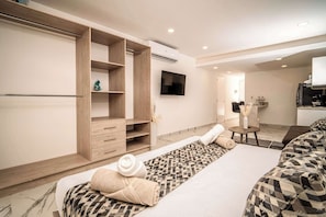 Una habitación de hotel con cama, televisión, armario y una pequeña zona de estar.
