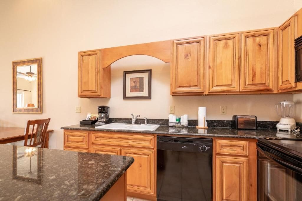 A kitchen with wooden cabinets, a granite countertop, a dishwasher, and a toaster.