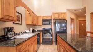 A kitchen with wooden cabinets, a microwave, a stove, and a refrigerator. - The Lodges at Table Rock Lake (Branson)