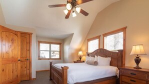 A bedroom with a wooden bed, a ceiling fan, two bedside lamps, and a wooden wardrobe. - The Lodges at Table Rock Lake (Branson)