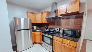 A kitchen with wooden cabinets, a stainless steel refrigerator, a stove, and a microwave. - Helix / King Bed / Elevator  Adjustable Desk (Philadelphia)