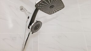A showerhead with a square design and multiple holes, attached to a wall-mounted shower system. - Helix / King Bed / Elevator  Adjustable Desk (Philadelphia)