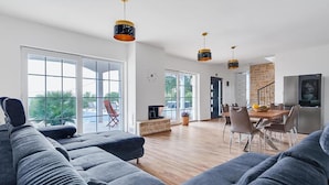 A modern living room with a large sectional sofa, a dining area with a wooden table and chairs, and a kitchen with a refrigerator and a television. - Beautiful home in Benkovac (Benkovac)