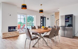 Eine moderne Küche mit Esstisch, Stühlen, einem Kühlschrank und Pendelleuchten.