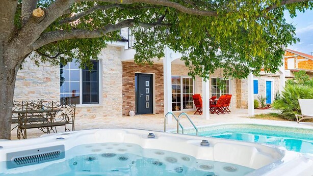 A pool area with a hot tub, outdoor seating, and a stone building with a door and windows. - Beautiful home in Benkovac (Benkovac)