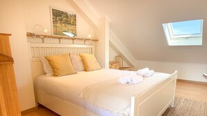 A bedroom with a bed, a window, a painting, and a wooden floor.