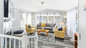 A living room with a sofa, two armchairs, a coffee table, and a TV. - Feather Trail Guest House - 3BR Cozy Family Stay (Nekoosa)