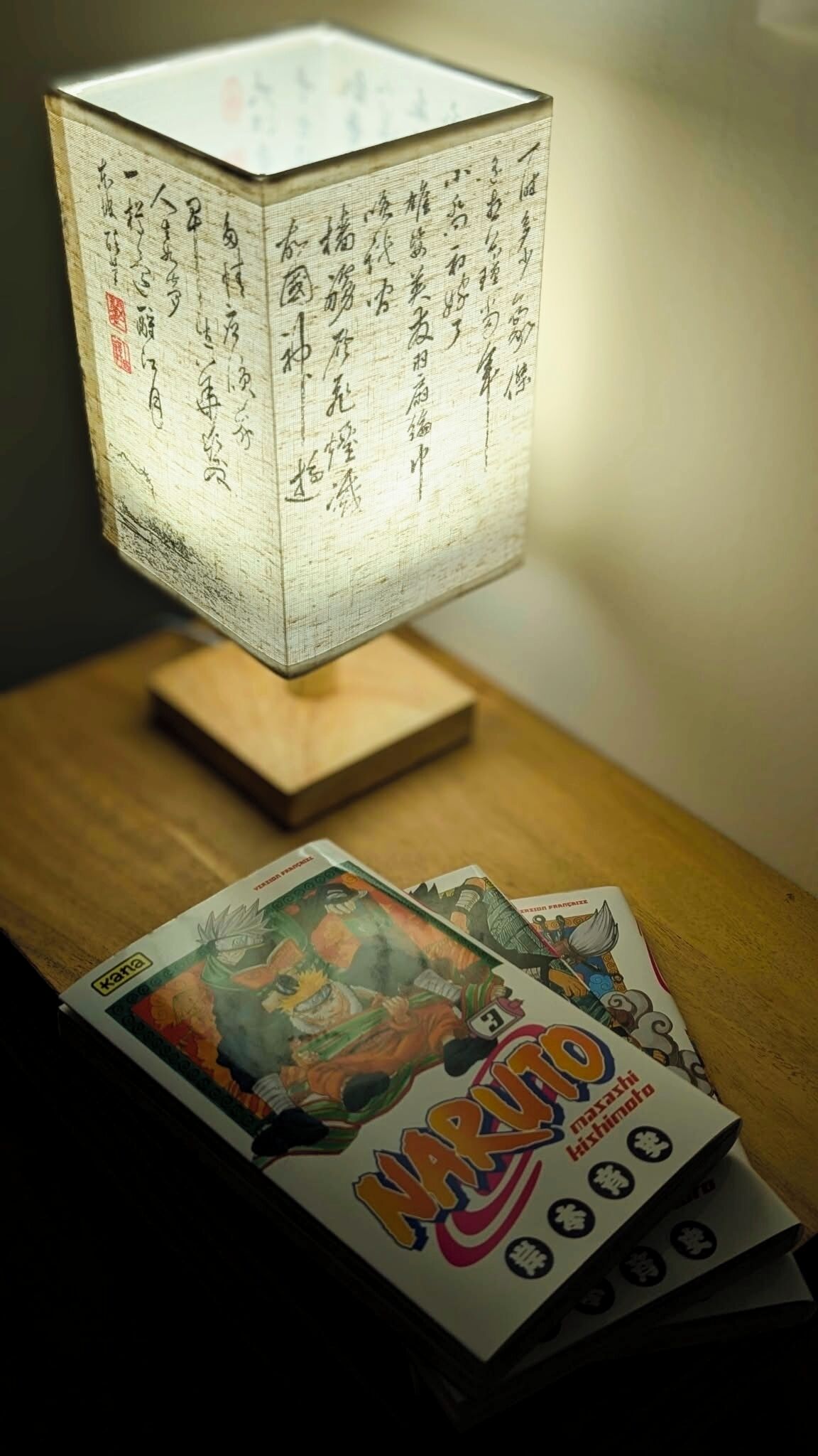 Un farol tradicional japonés sobre una mesa de madera con libros de manga.