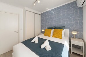 Ein Hotelzimmer mit einem Bett, einem Nachttisch, einer Wand mit nautischem Muster und einer Tür.