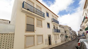 Vista de una calle con un edificio que tiene balcones, contraventanas y fachada de azulejos.