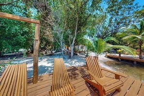 A wooden deck with lounge chairs, a wooden pergola, and a small water feature. - Charming duplex with full Kitchen & WiFi - near dining & stunning attractions (Placencia)