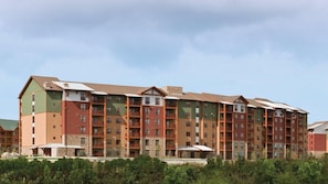A multi-story hotel with a mix of brick and stone facades, balconies, and a flat roof. - Great Smokies Lodge 2BR Deluxe – Water Park & Outdoor Adventure (Sevierville)