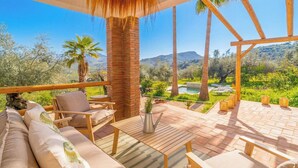 A terrace with a wooden table, chairs, and a view of a pool and mountains. - Casa Olivo Vélez-Málaga by Ruralidays (Málaga)