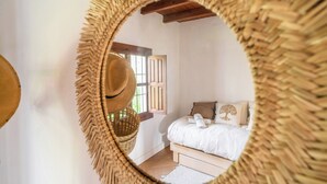 A bedroom with a bed, a window, and a woven mirror. - Casa Olivo Vélez-Málaga by Ruralidays (Málaga)