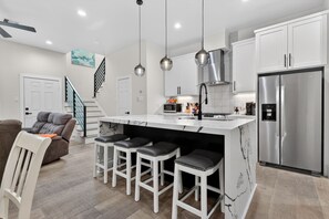 A modern kitchen with a marble island, stainless steel appliances, and pendant lighting. - East End Stay | Near Daikin Park & Downtown (Houston)