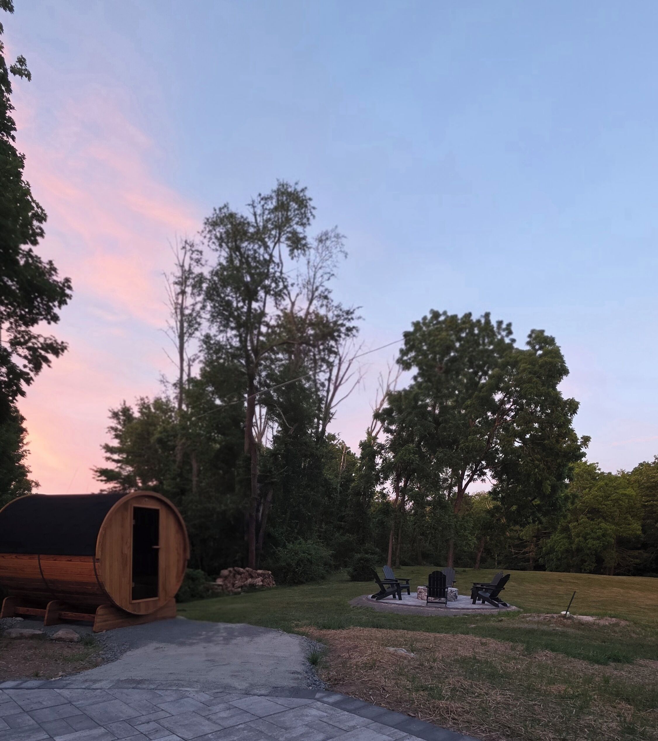 A wooden barrel structure, outdoor seating, and a grassy area with trees.