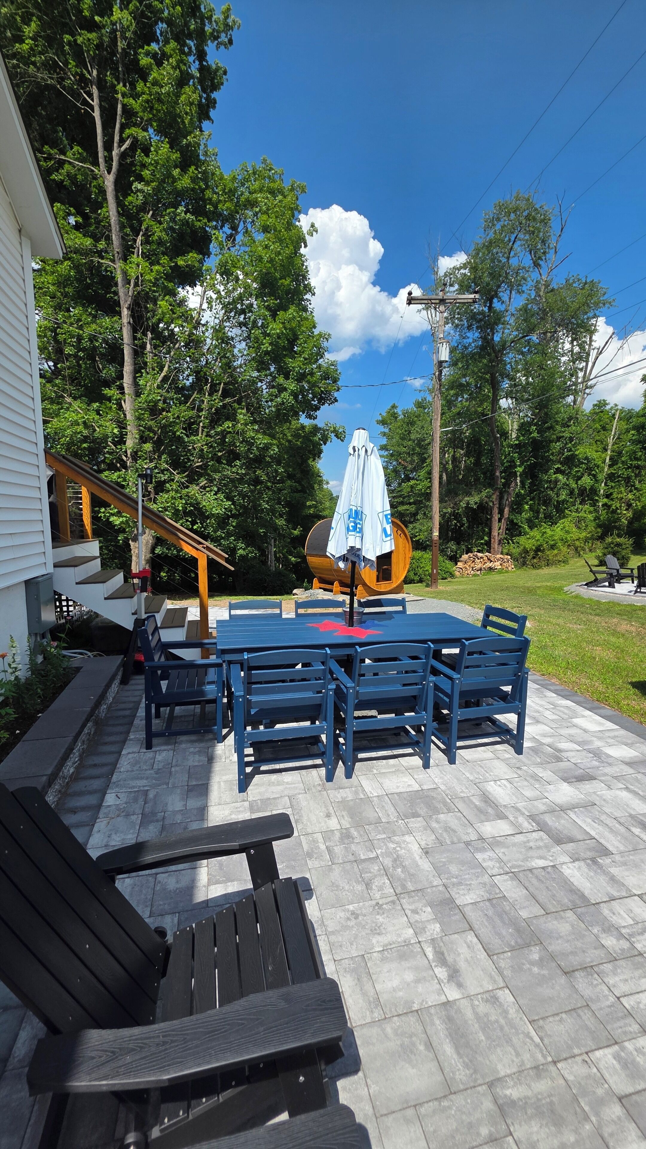 Une terrasse avec une table et des chaises, un banc en bois et un espace abrité avec un tonneau.