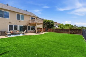 A house with a covered patio, a lawn, and a wooden fence.