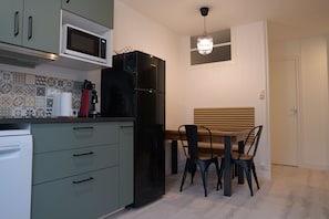 Eine kompakte Küche mit Mikrowelle, Kühlschrank und einem Essbereich mit Holztisch und Stühlen.