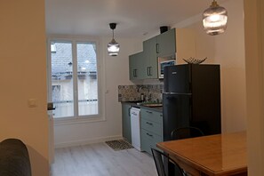 Eine Küche mit Kühlschrank, Geschirrspüler und einem Esstisch mit Stühlen.