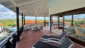 Ett takförsett utomhusområde med sittplatser, en pool och utsikt över ett bostadsområde.