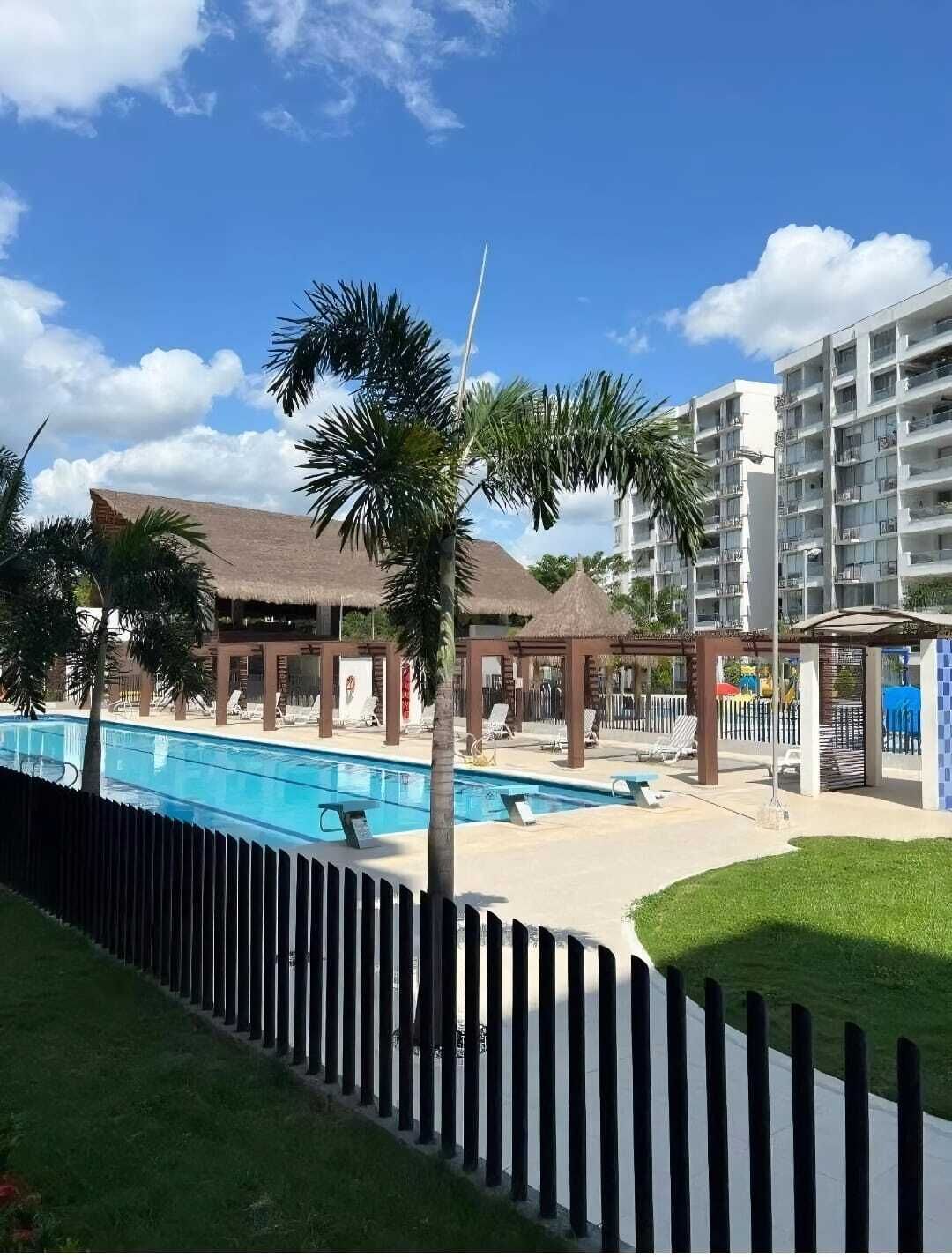A resort with a swimming pool, palm trees, and a building with balconies.