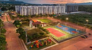 A residential complex with multiple apartment buildings, a playground, and a sports court. - Apartamento Familiar en Peñazul Ricaurte Vista a Piscinas Colombia (Ricaurte)