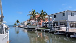 A marina with boats docked, a clear sky, and buildings with palm trees. - The Friendly Pelican
2-BDR 2-BATH on a canal w/AC in Big Pine Key (Big Pine Key)