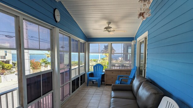 A covered porch with a view of the ocean, a brown leather sofa, and blue chairs. - The Friendly Pelican
2-BDR 2-BATH on a canal w/AC in Big Pine Key (Big Pine Key)