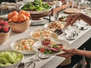 A buffet table with various dishes, including a salad, fruit, and a dessert with a garnish. - THE BARAI HUA HIN – The Unbound Collection by Hyatt (Hua Hin)