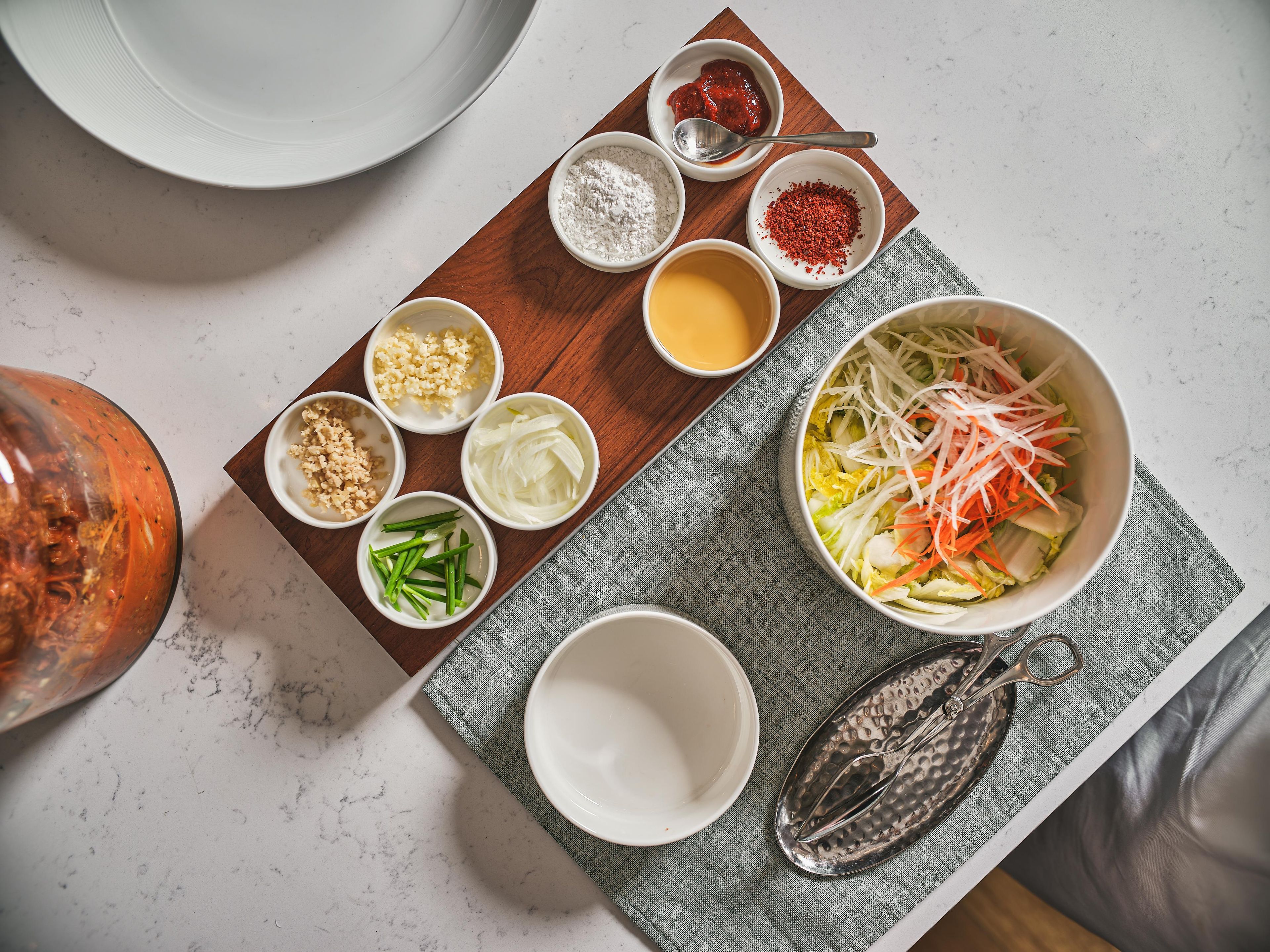 A table with various food ingredients and a bowl of salad.