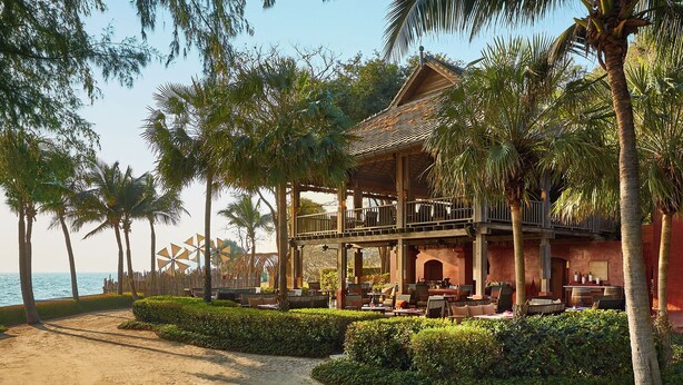 Ein Strandhotel mit Außenbereich, Palmen und Meerblick.