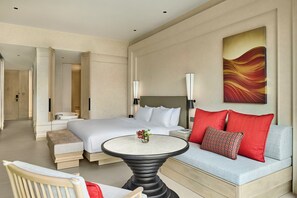 Ein Hotelzimmer mit Bett, Sofa, rundem Tisch und einem Gemälde an der Wand.