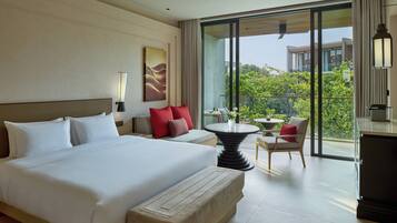 A modern hotel room with a large bed, a small table, a chair, and a balcony with a view.