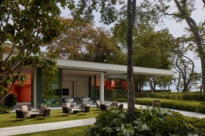 A modern outdoor seating area with tables and chairs, surrounded by lush greenery and trees. - THE BARAI HUA HIN – The Unbound Collection by Hyatt (Hua Hin)
