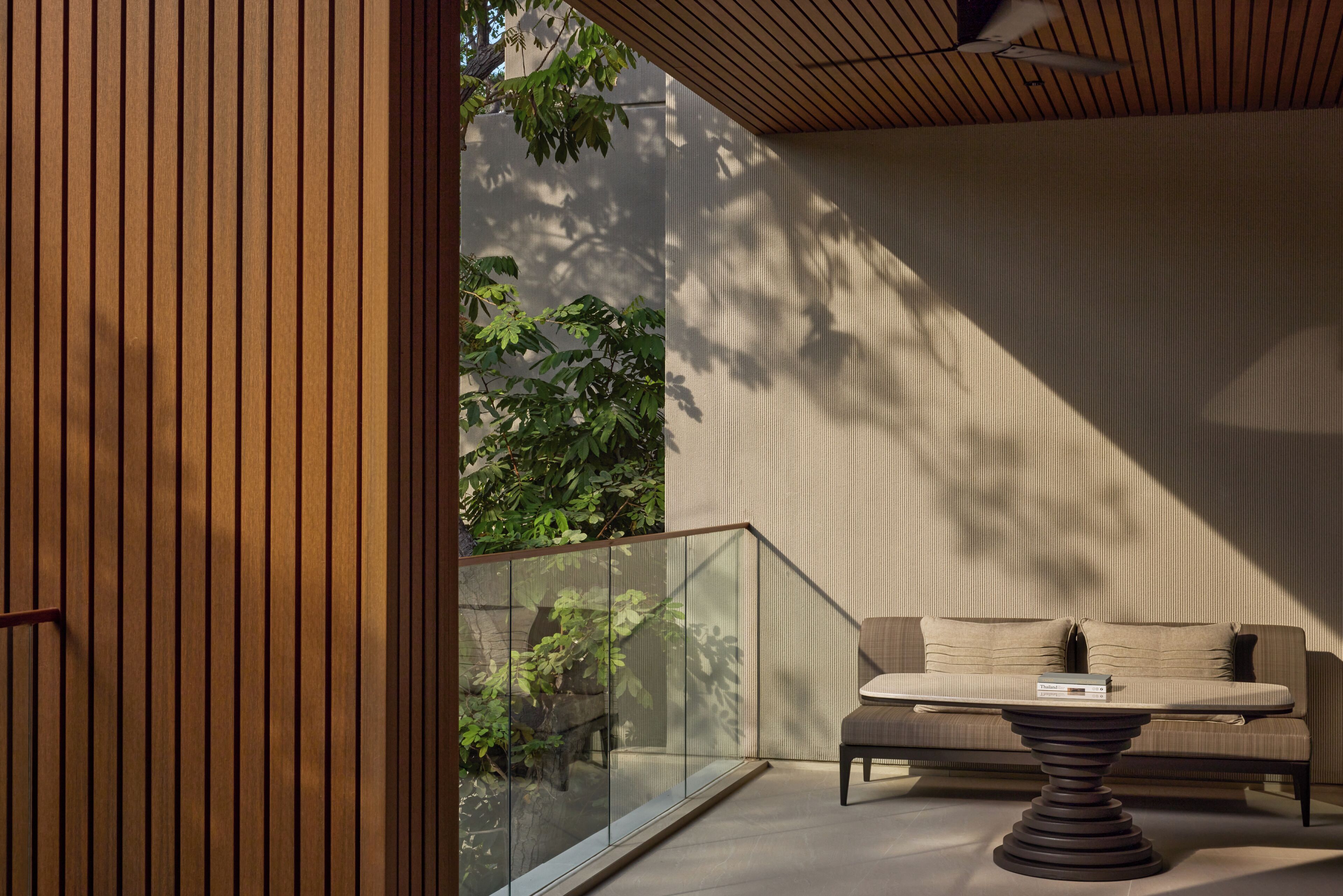 A modern interior with a glass balustrade, a sofa, and a table.
