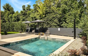 A rectangular swimming pool with a tiled deck, surrounded by a fence, and shaded by umbrellas. - Stunning home in Krsan (Krsan)