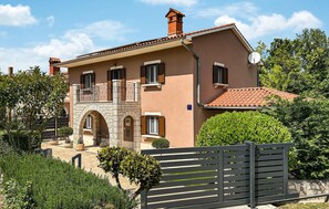 A two-story building with a stone archway entrance, a balcony with a railing, and a satellite dish. - Stunning home in Krsan (Krsan)