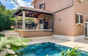Ein Haus mit Schwimmbecken, einer überdachten Terrasse und einer Treppe zum Eingang.