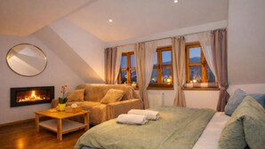 A cozy bedroom with a bed, a sofa, a small table, and a fireplace. - Penzion Quest Loket (Loket)