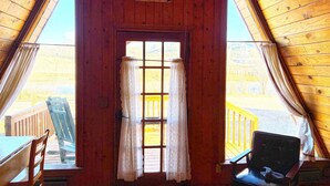 Ett rum med träpanel på väggarna, ett stort fönster, en dörr och två stolar.