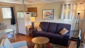 A compact living space with a sofa, armchair, small round table, and a desk with a lamp. - Cozy River Cabin with Arkansas River View (Howard)